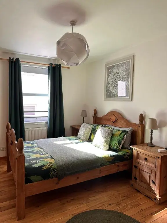 a bedroom with a wooden bed and a window at City centre apartment next to Bus and Train Station in Inverness