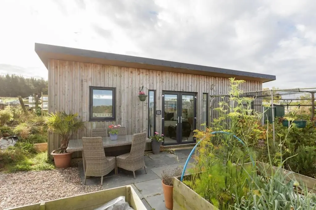 a small house with a table and chairs in a garden at Cosy and modern 1 bedroom garden house - very dog friendly! in Tarves