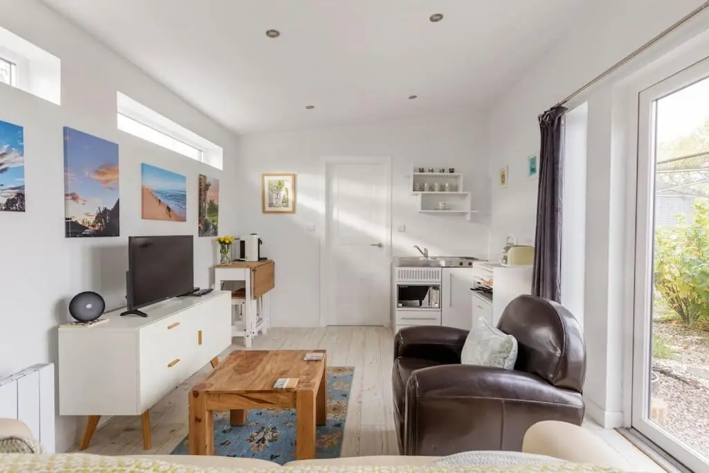 a living room with a tv and a couch and a table at Cosy and modern 1 bedroom garden house - very dog friendly! in Tarves