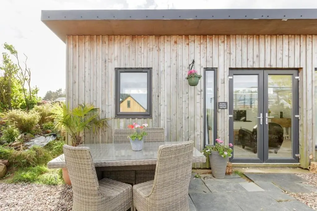 a patio with a table and chairs and a building at Cosy and modern 1 bedroom garden house - very dog friendly! in Tarves