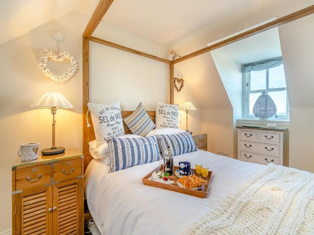 a bedroom with a bed with a tray of food on it at The Old Net Shed in Whitehills