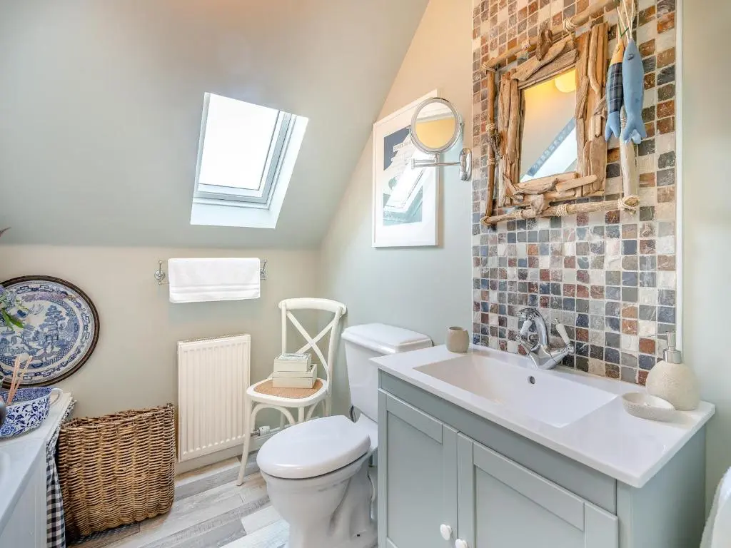 a bathroom with a toilet and a sink and a mirror at The Old Net Shed in Whitehills