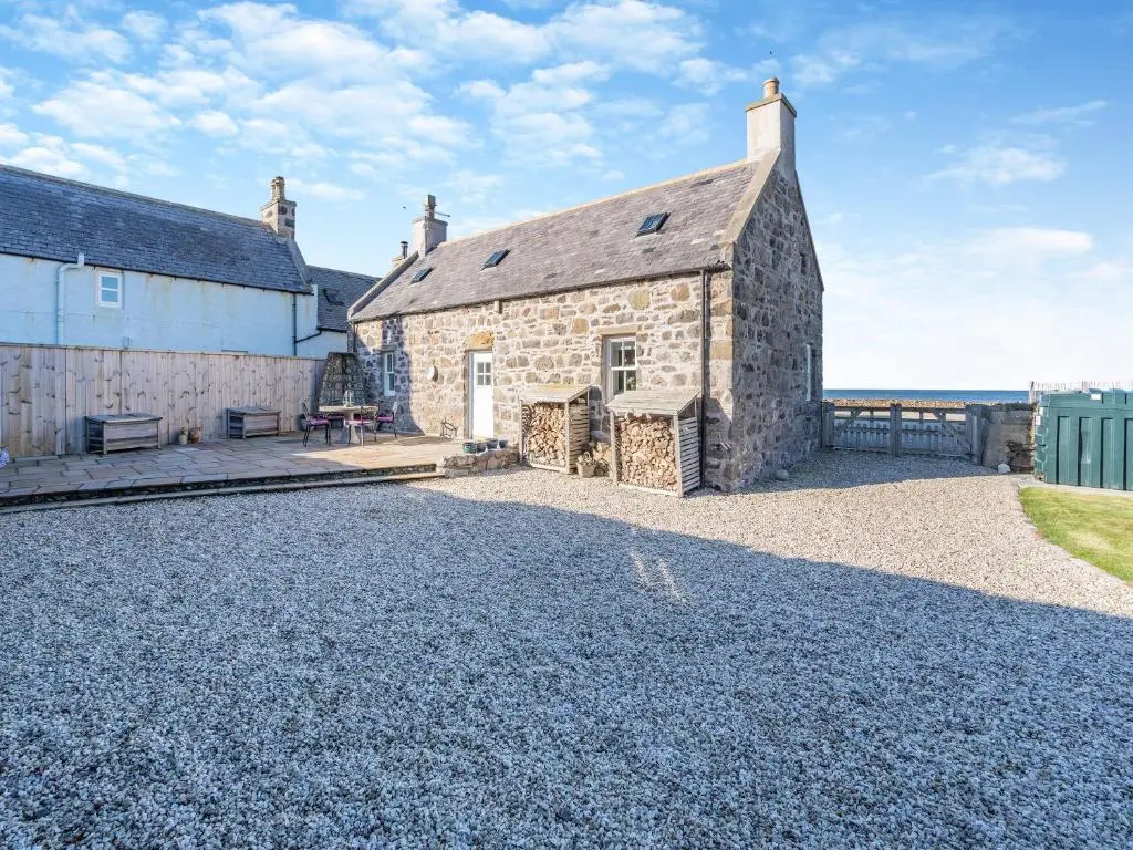 an external view of a stone building with a gravel driveway at The Old Net Shed in Whitehills