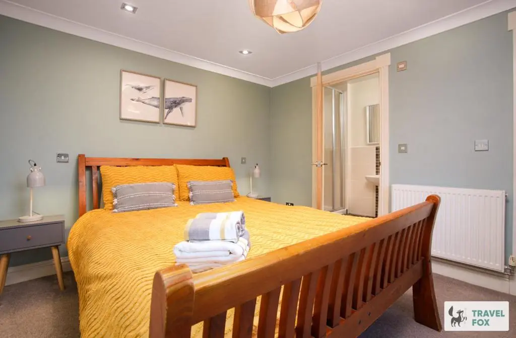 a bedroom with a large yellow bed with a bench at Daisy Cottage - Two bed country retreat with hot tub in Turriff