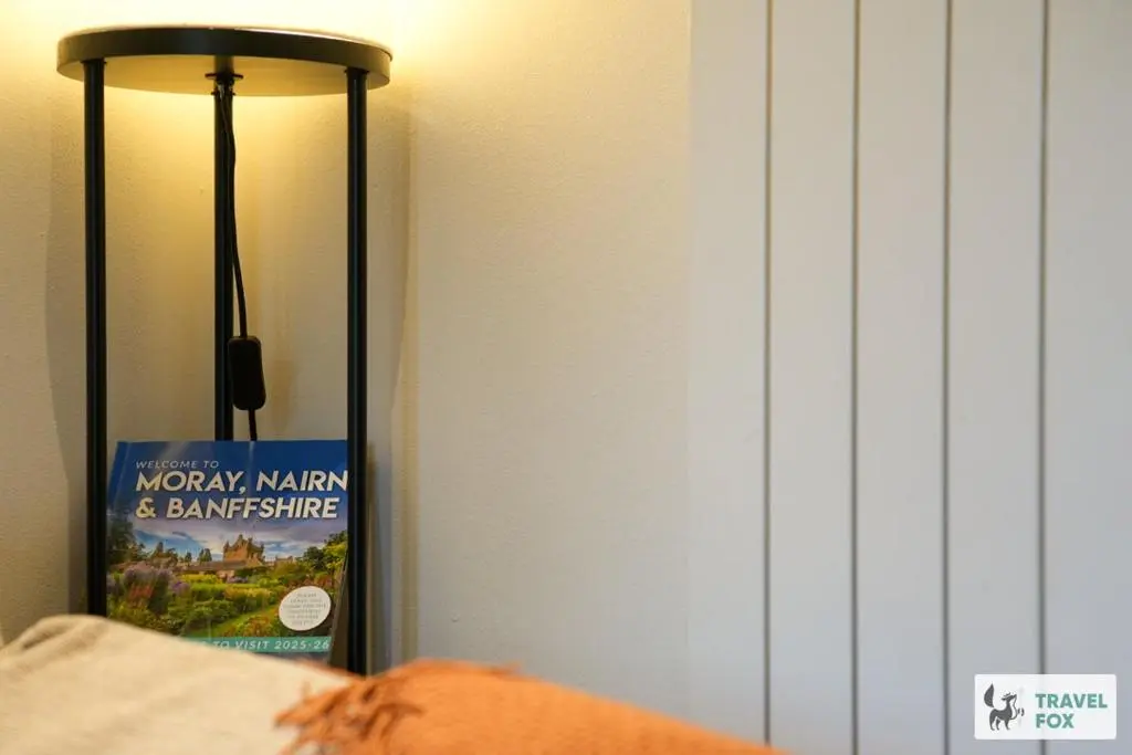 a book sitting next to a lamp next to a bed at Daisy Cottage - Two bed country retreat with hot tub in Turriff