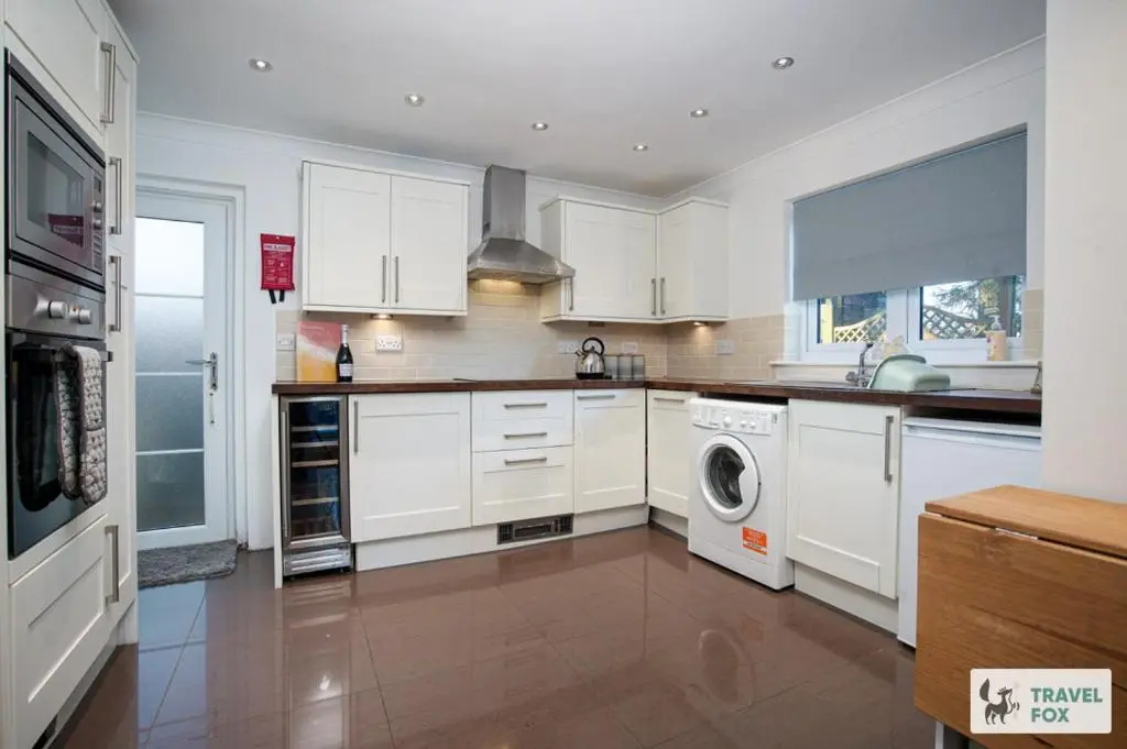 a kitchen with white cabinets and a washer and dryer at Daisy Cottage - Two bed country retreat with hot tub in Turriff
