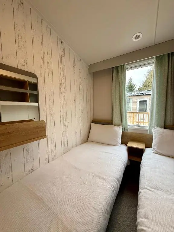 two beds in a small room with a window at The Telford Van - Beautiful, luxury static caravan in Aberlour