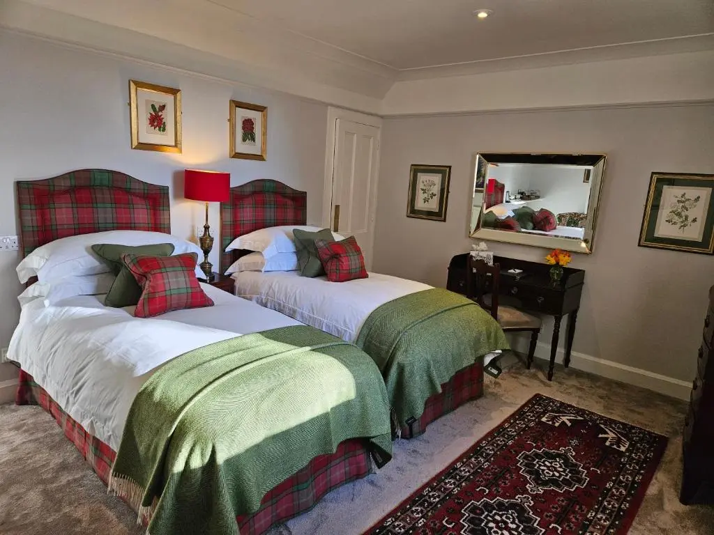 a bedroom with two beds and a mirror at Craggan in Ballater