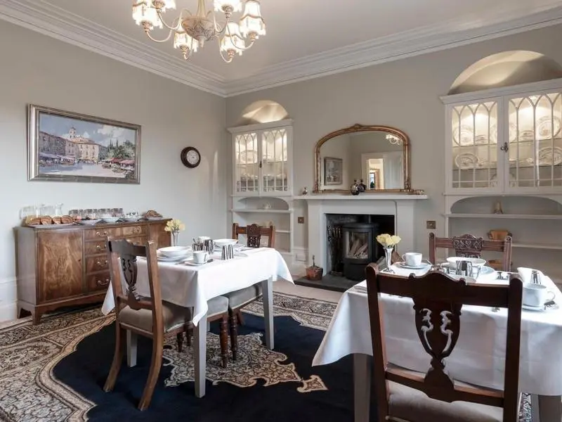 a dining room with a table and a fireplace at Craggan in Ballater