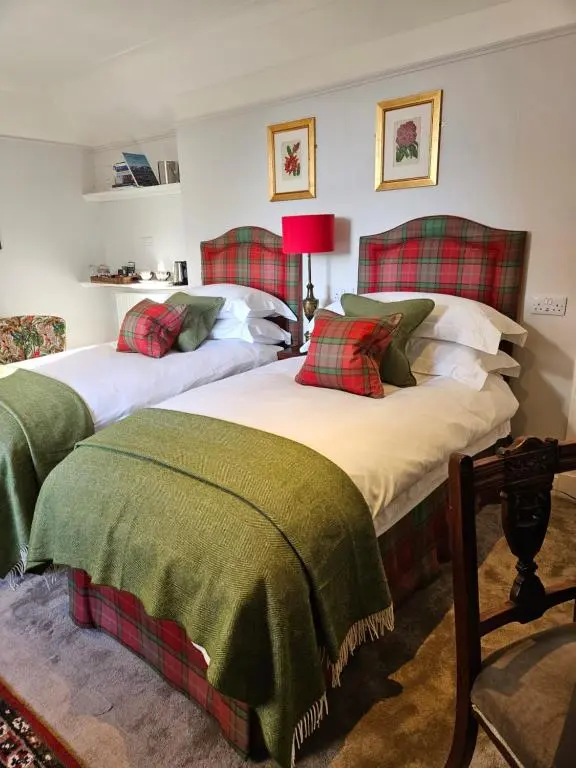 two beds with green and red blankets in a room at Craggan in Ballater