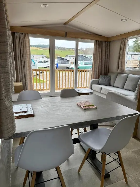 a living room with a large table and chairs at The Spey Van - Beautiful, luxury static caravan in Aberlour