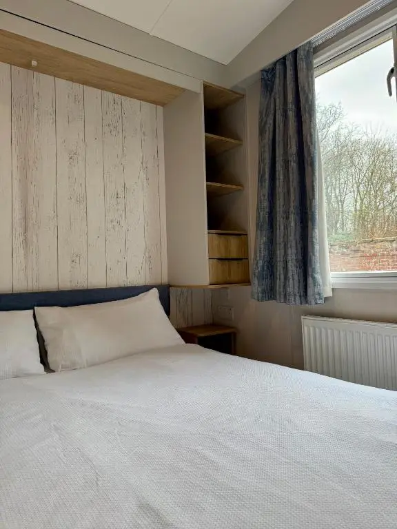 a bedroom with a white bed and a window at The Spey Van - Beautiful, luxury static caravan in Aberlour