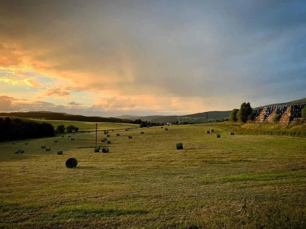 a field full of hay bales in the sunset at The Springer Van - Beautiful, luxury static caravan in Aberlour
