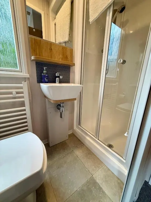 a bathroom with a shower and a toilet and a sink at The Springer Van - Beautiful, luxury static caravan in Aberlour