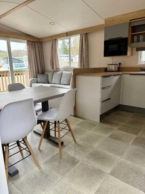 a kitchen and living room with a table and chairs at The Springer Van - Beautiful, luxury static caravan in Aberlour