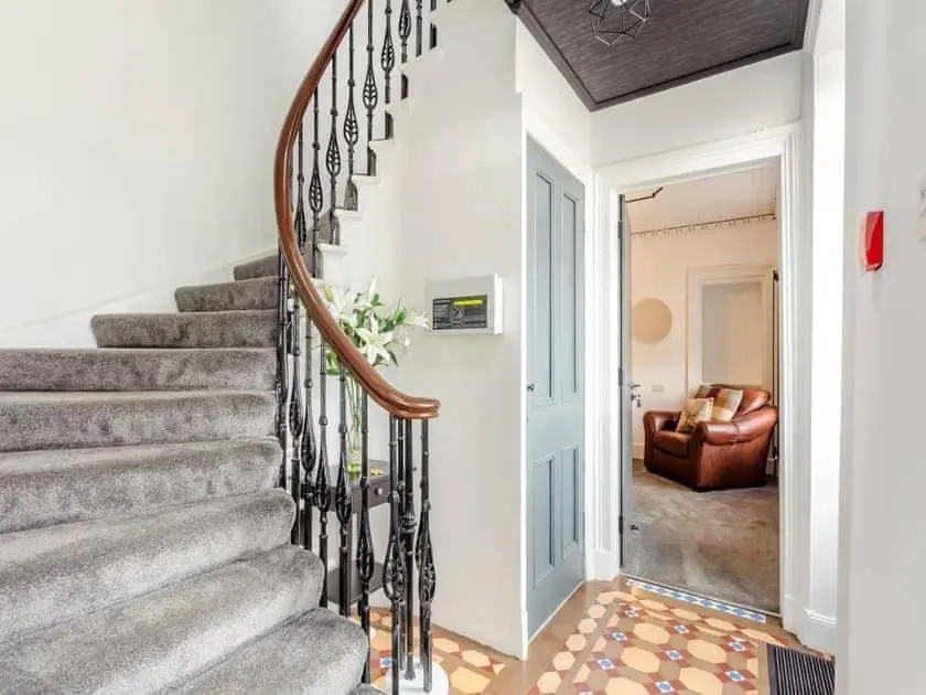 a staircase in a living room with a couch at LANGLEY LODGE 7 Double Bedrooms with SMART TVs, 6 Bathrooms, Fully Equipped Kitchen, Ample PARKING, Wifi, dishwasher, Garden, GREAT CENTRAL LOCATION Ideal for BUSINESS and TRADES TEAMS For Long Stays contact Langley Cottages & Serviced Apartments in Wick