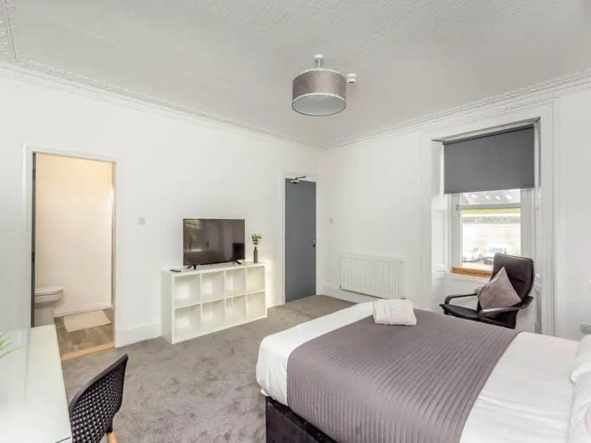 a white bedroom with a bed and a tv at LANGLEY LODGE 7 Double Bedrooms with SMART TVs, 6 Bathrooms, Fully Equipped Kitchen, Ample PARKING, Wifi, dishwasher, Garden, GREAT CENTRAL LOCATION Ideal for BUSINESS and TRADES TEAMS For Long Stays contact Langley Cottages & Serviced Apartments in Wick