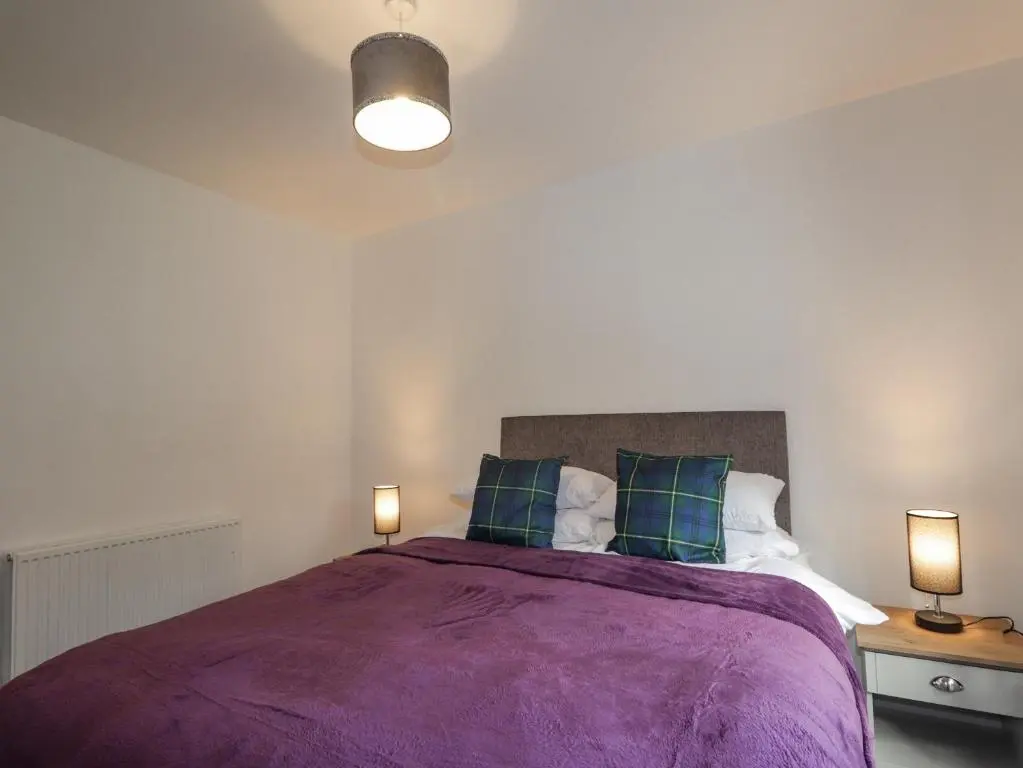a bedroom with a large purple bed with two lamps at Fresh Fields in Dingwall