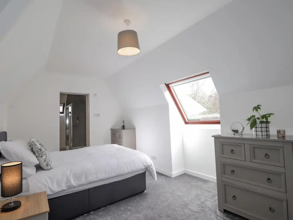 a bedroom with a bed and a dresser and a window at Fresh Fields in Dingwall