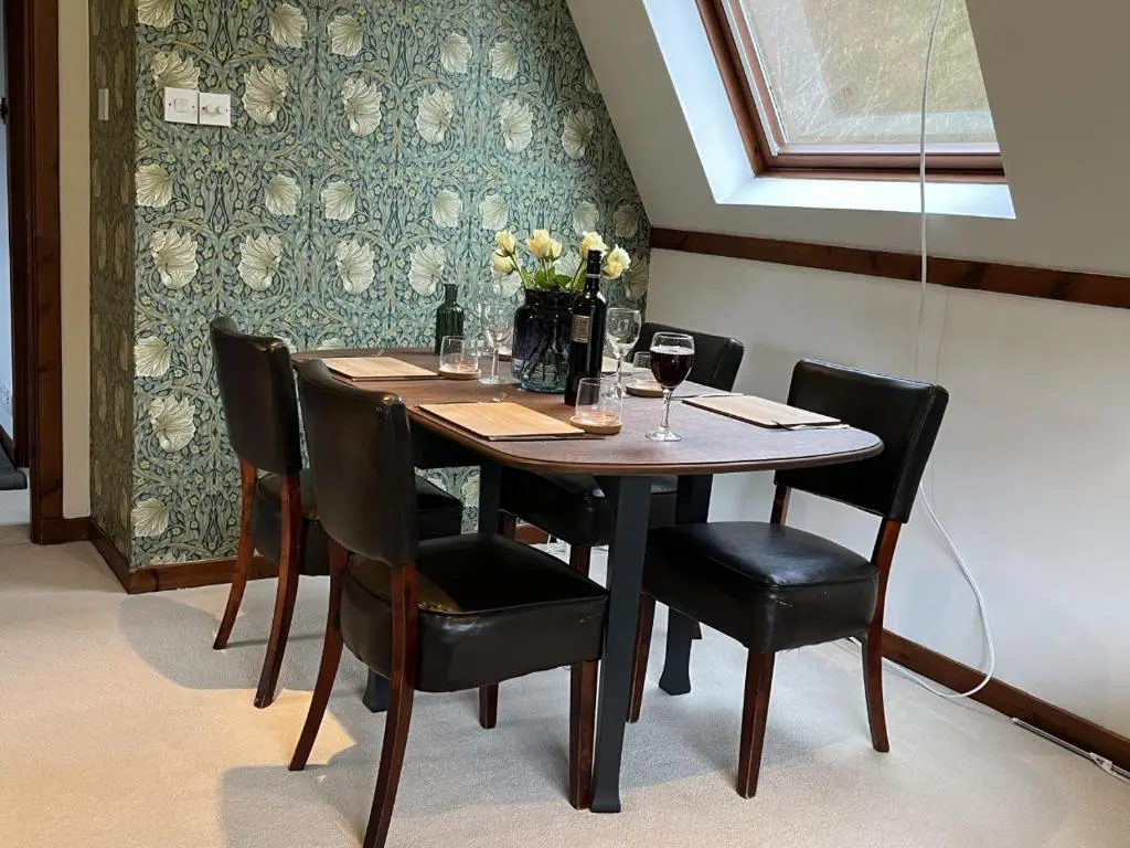 a dining room table with chairs and a vase of flowers at Caledonia Lodge in Spean Bridge