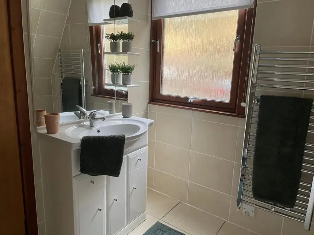 a bathroom with a sink and a window and a mirror at Caledonia Lodge in Spean Bridge