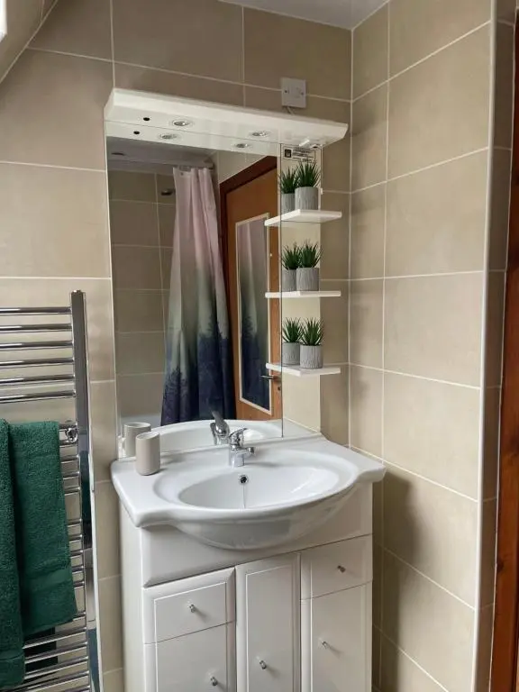 a bathroom with a sink and a mirror at Caledonia Lodge in Spean Bridge