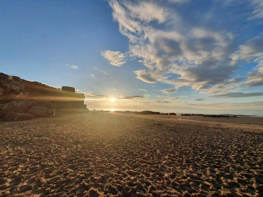 a beach with the sun setting on the horizon at Lyons Retreat in Lossiemouth