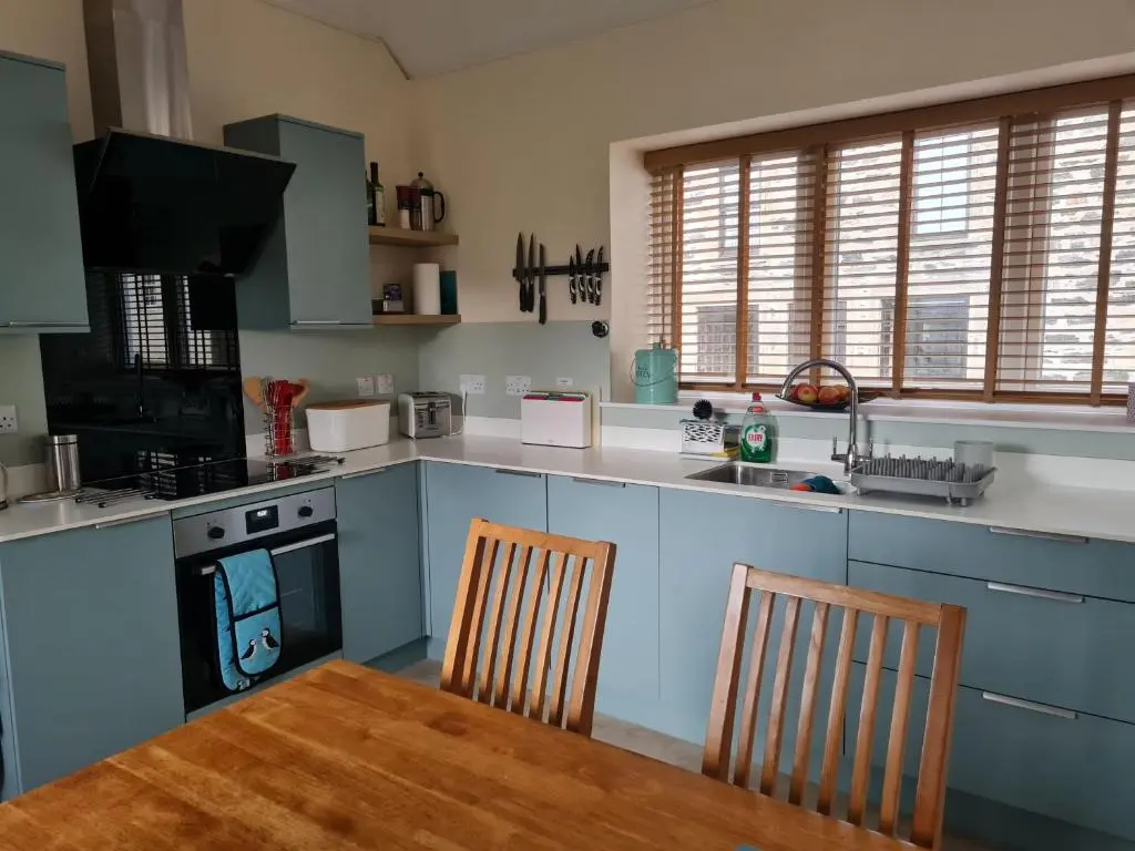 a kitchen with blue cabinets and a table and chairs at Old Police Station, Portsoy in Portsoy