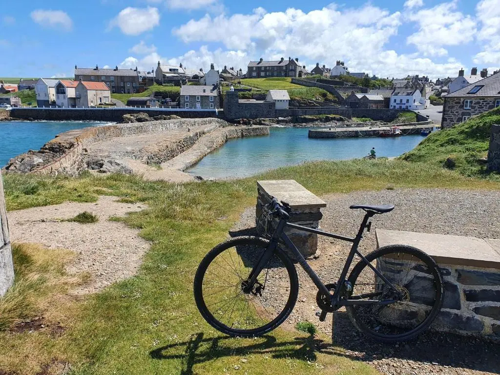 a bike parked next to a bench next to a river at Old Police Station, Portsoy in Portsoy