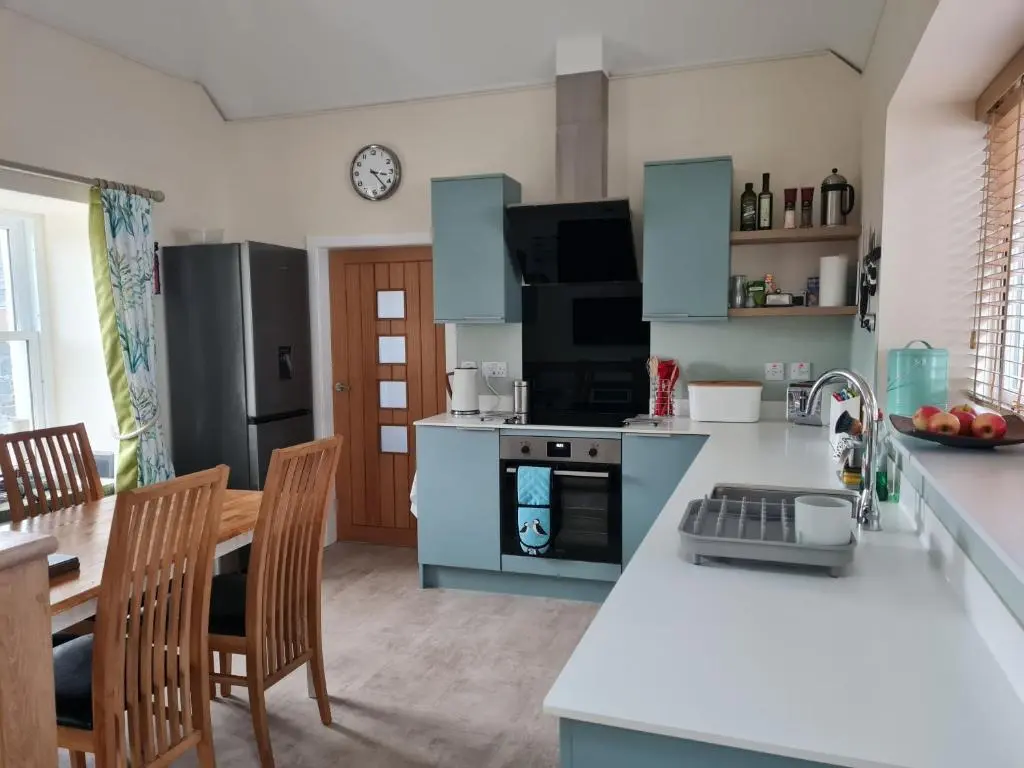 a kitchen with blue cabinets and a table and chairs at Old Police Station, Portsoy in Portsoy