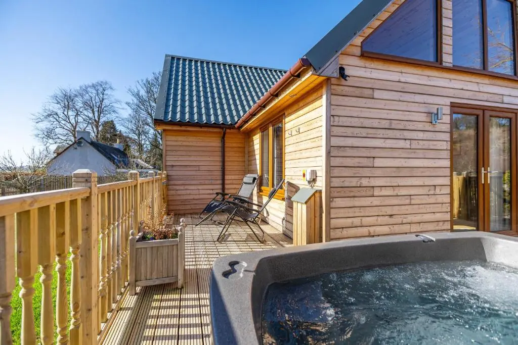 a small wooden house with a hot tub on a deck at Roe Deer Lodge with Hot Tub in Cray