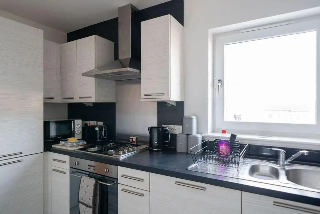 a kitchen with white cabinets and a sink and a window at Hope House - 2 bedroom flat in Aberdeen