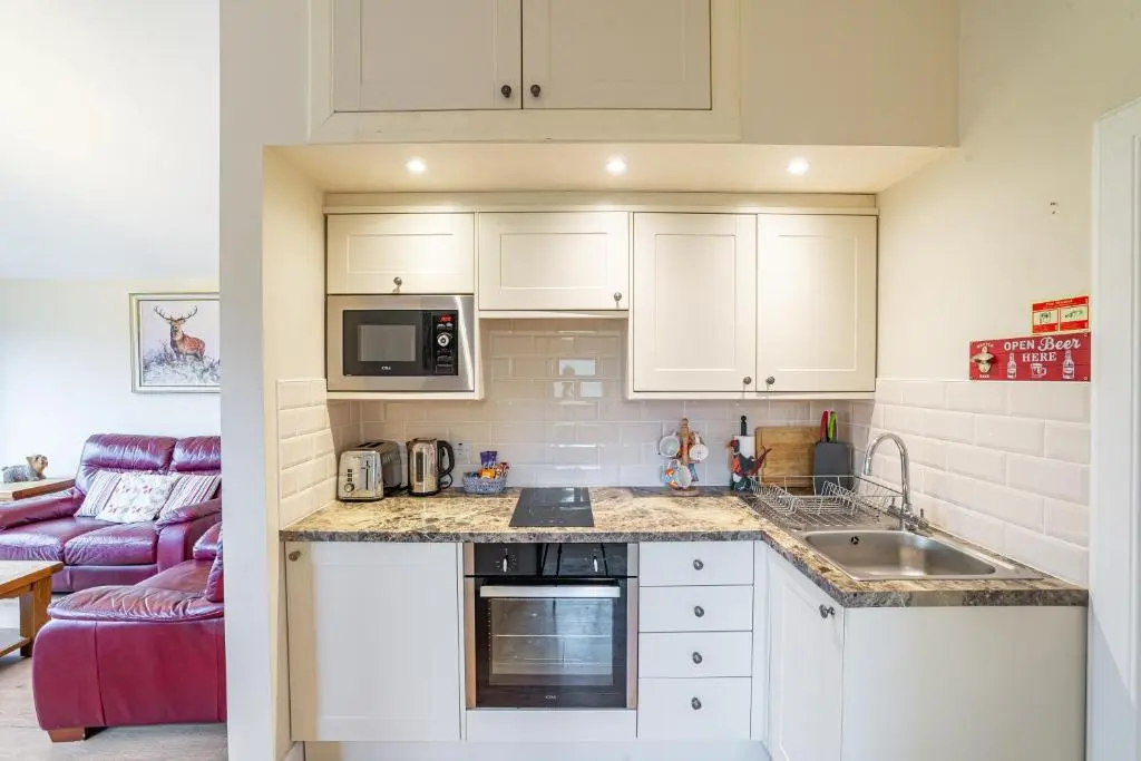a kitchen with white cabinets and a purple couch at Pine Marten Lodge with Hot Tub in Cray
