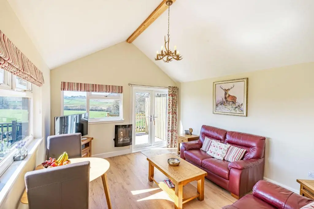 a living room with a couch and a table at Pine Marten Lodge with Hot Tub in Cray