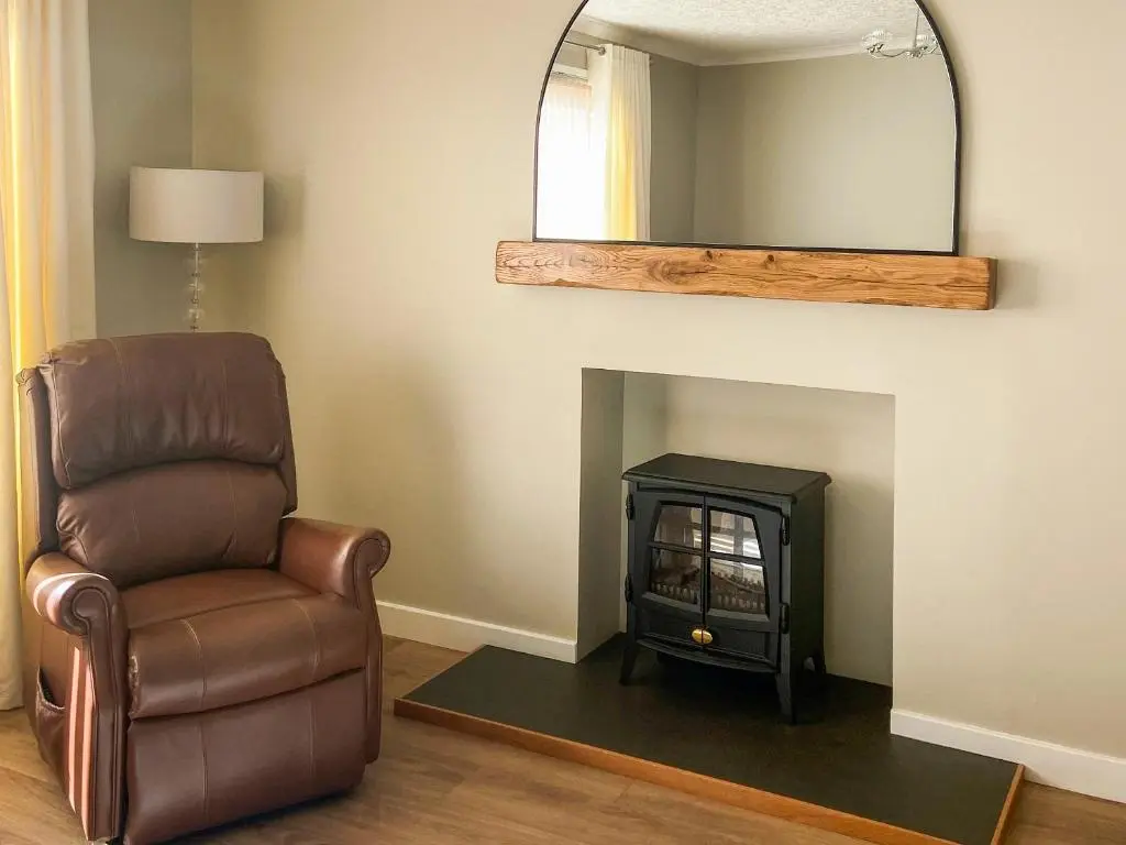 a living room with a chair and a mirror at Cathwill in Newtonmore