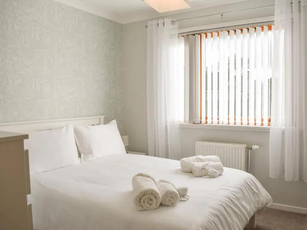 a bedroom with a white bed with towels on it at Cathwill in Newtonmore