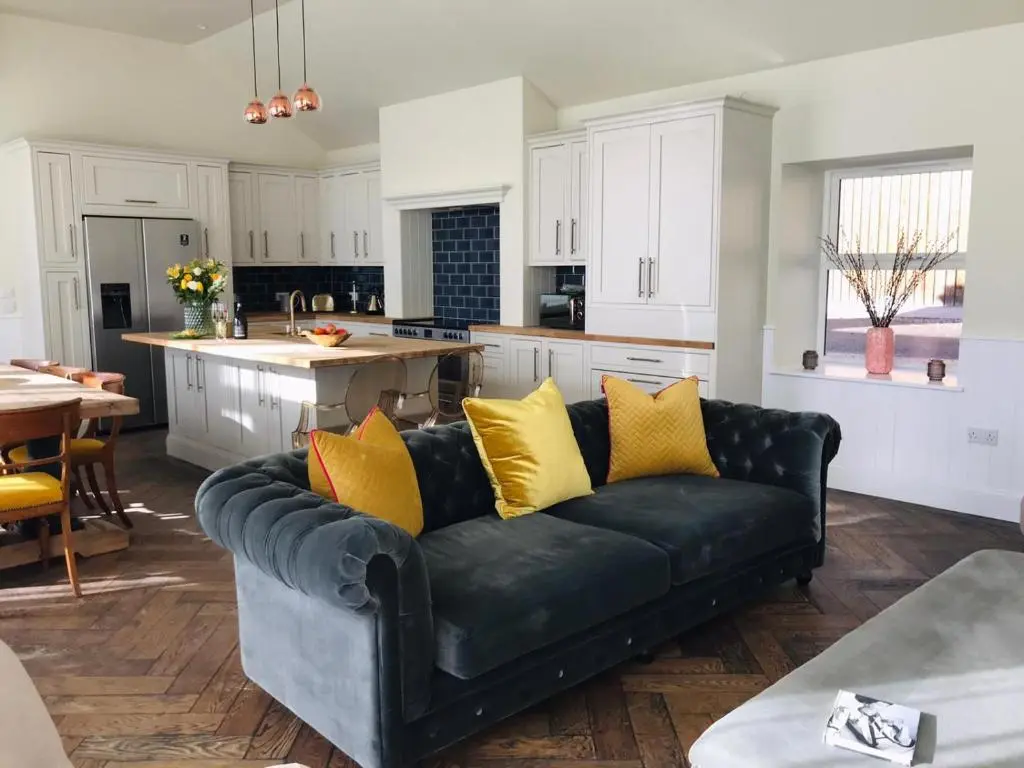 a black couch with yellow pillows in a kitchen at Gardeners cottage in Pitlochry