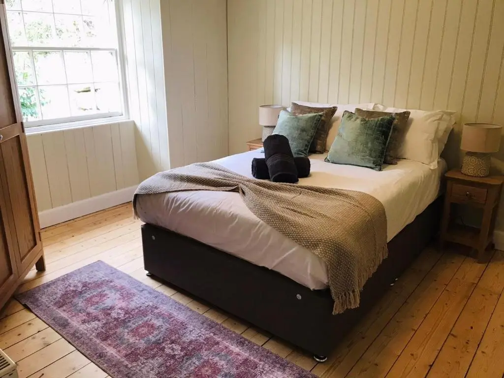 a bedroom with a large bed with pillows at Gardeners cottage in Pitlochry