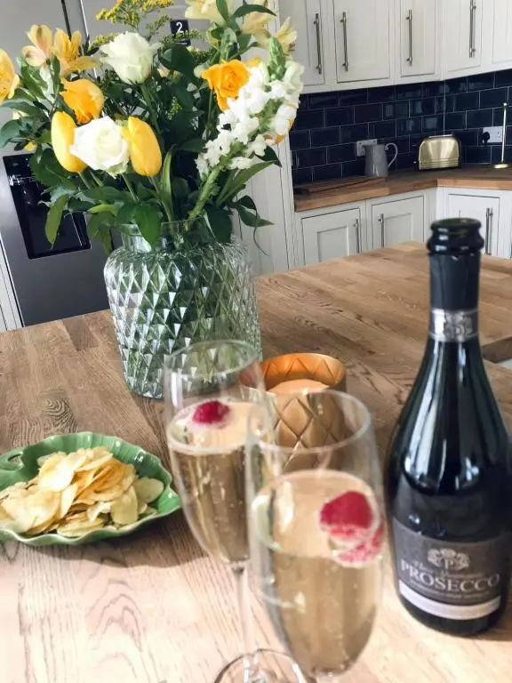 a table with two glasses of wine and a vase of flowers at Gardeners cottage in Pitlochry