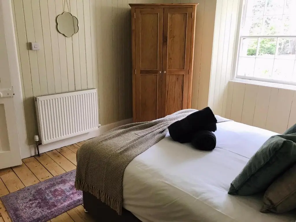 a bedroom with a large bed with a window at Gardeners cottage in Pitlochry