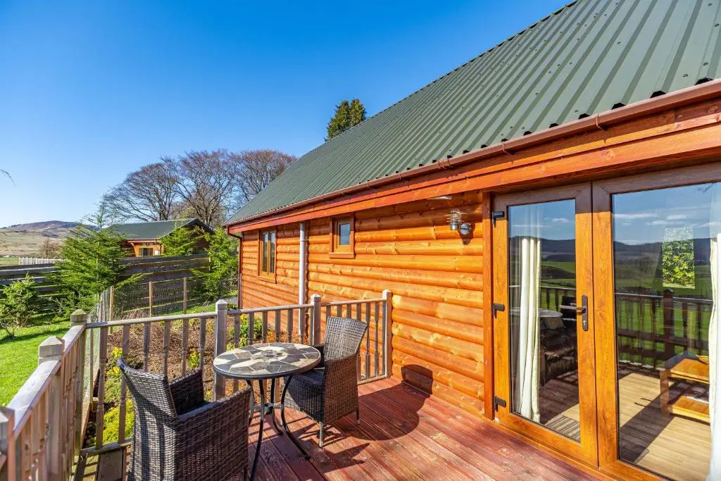 a wooden cabin with a table and chairs on a deck at Wildcat Lodge in Cray