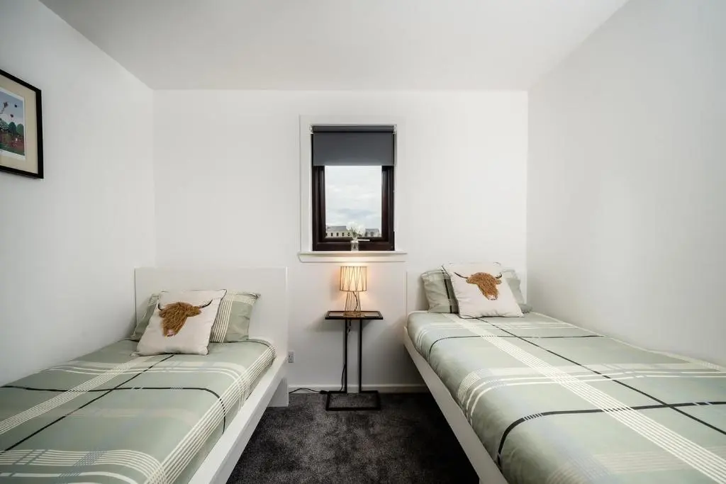 two beds in a room with white walls and a window at Ness Riverfront Holiday Home - City Centre in Inverness