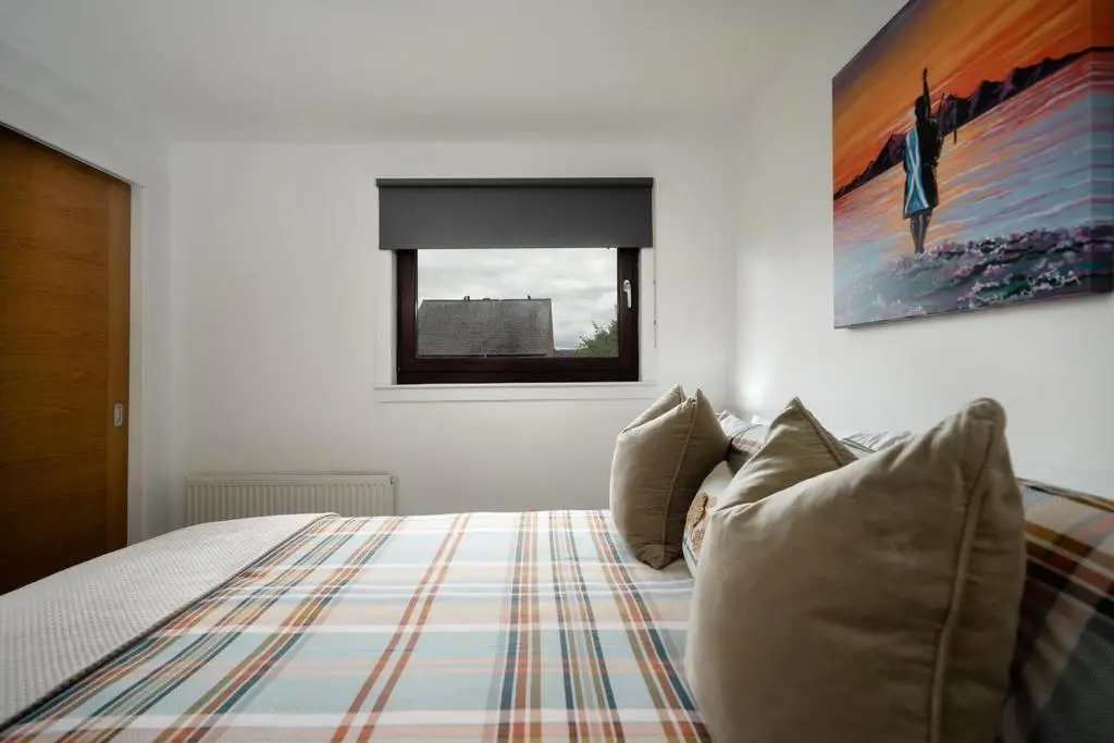 a bedroom with a bed with pillows and a window at Ness Riverfront Holiday Home - City Centre in Inverness