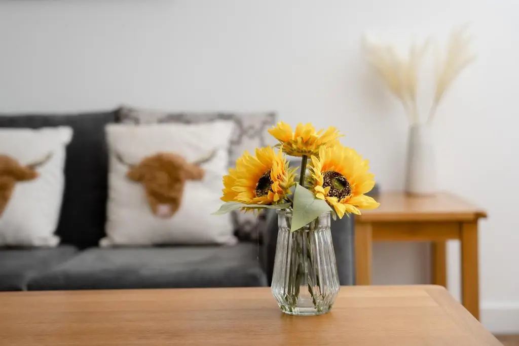 a vase filled with sunflowers sitting on a table at Ness Riverfront Holiday Home - City Centre in Inverness