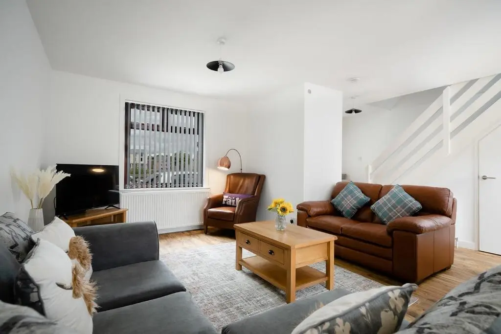 a living room with two couches and a table at Ness Riverfront Holiday Home - City Centre in Inverness