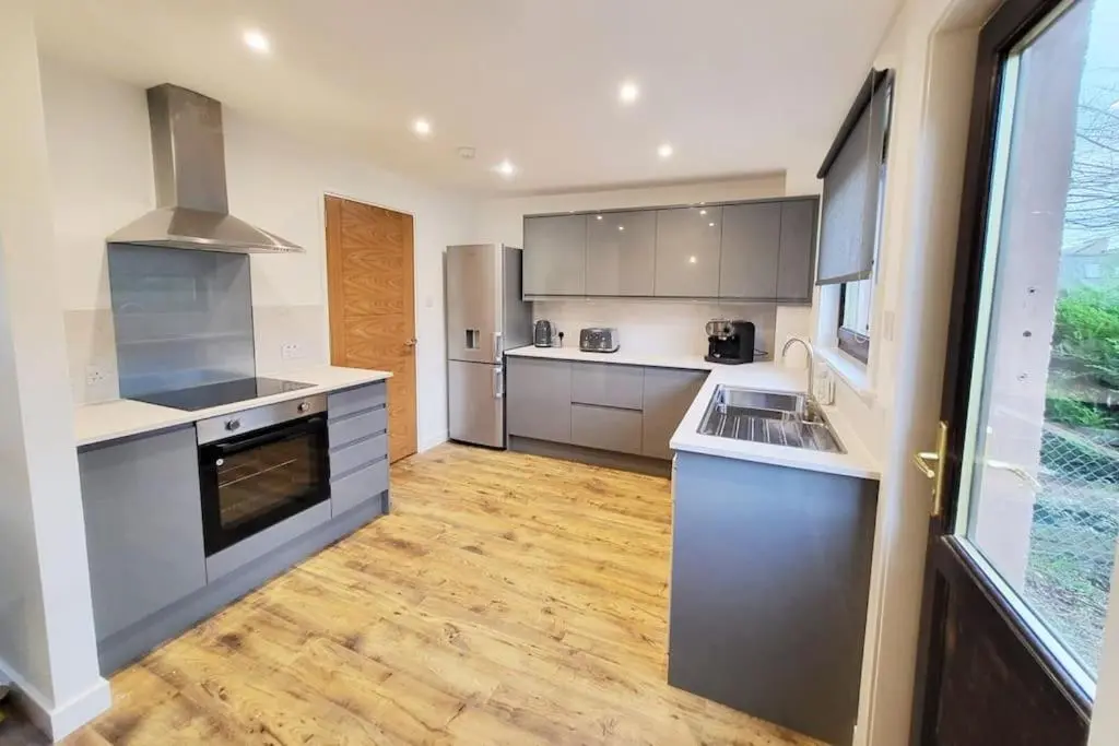 a kitchen with stainless steel appliances and a wooden floor at Ness Riverfront Holiday Home - City Centre in Inverness