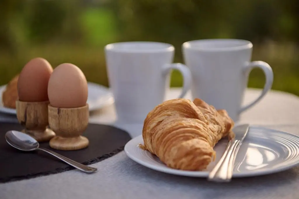 a plate of croissants and eggs on a table with two cups at The Dell at Glenlivet in Glenlivet