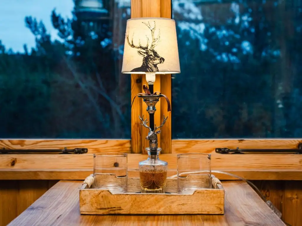 a table with a lamp and two glasses on it at Holiday Home Shepherds Hut by Interhome in Bearnock