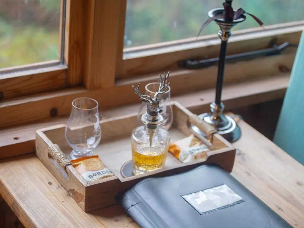 a table with a tray with two glasses and a lamp at Holiday Home Shepherds Hut by Interhome in Bearnock