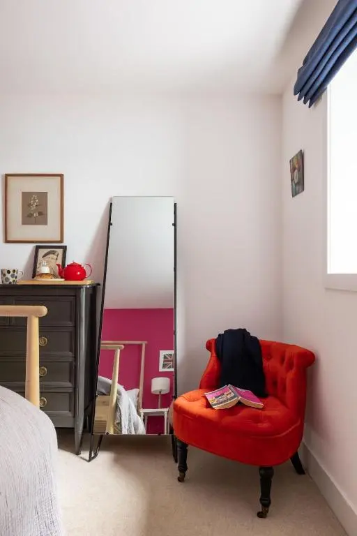 a red chair in a bedroom with a mirror at Number 4 Steading Cottage in Banchory